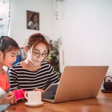 Lovely girl reading e-learning resources on the laptop computer with the assistance of her mom at home
1216335789