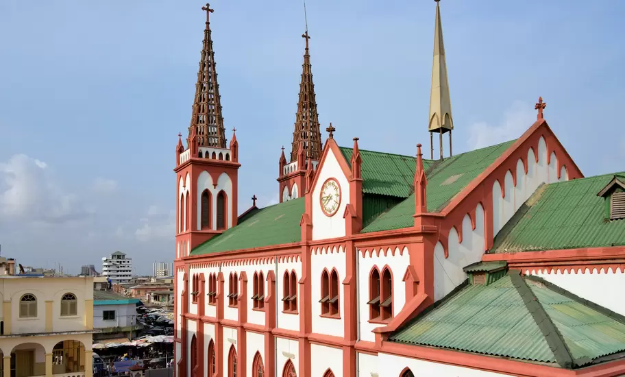 Red-and-white Gothic Revival Sacred Heart Cathedral in Lomé, Togo, with lattice spires and a green roof