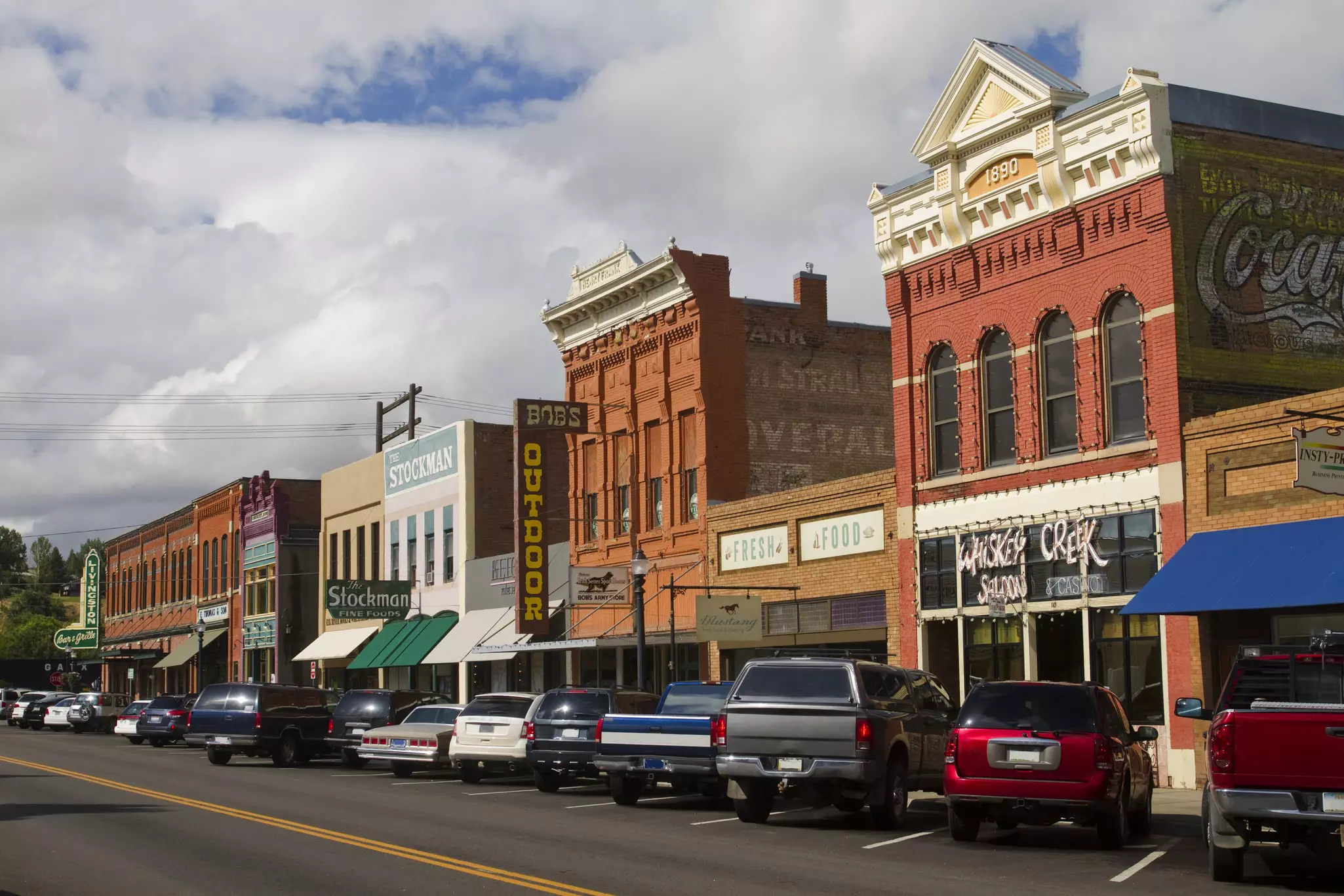 Cars parked along a street lined with red-brick buildings dating fromm the 1890s.