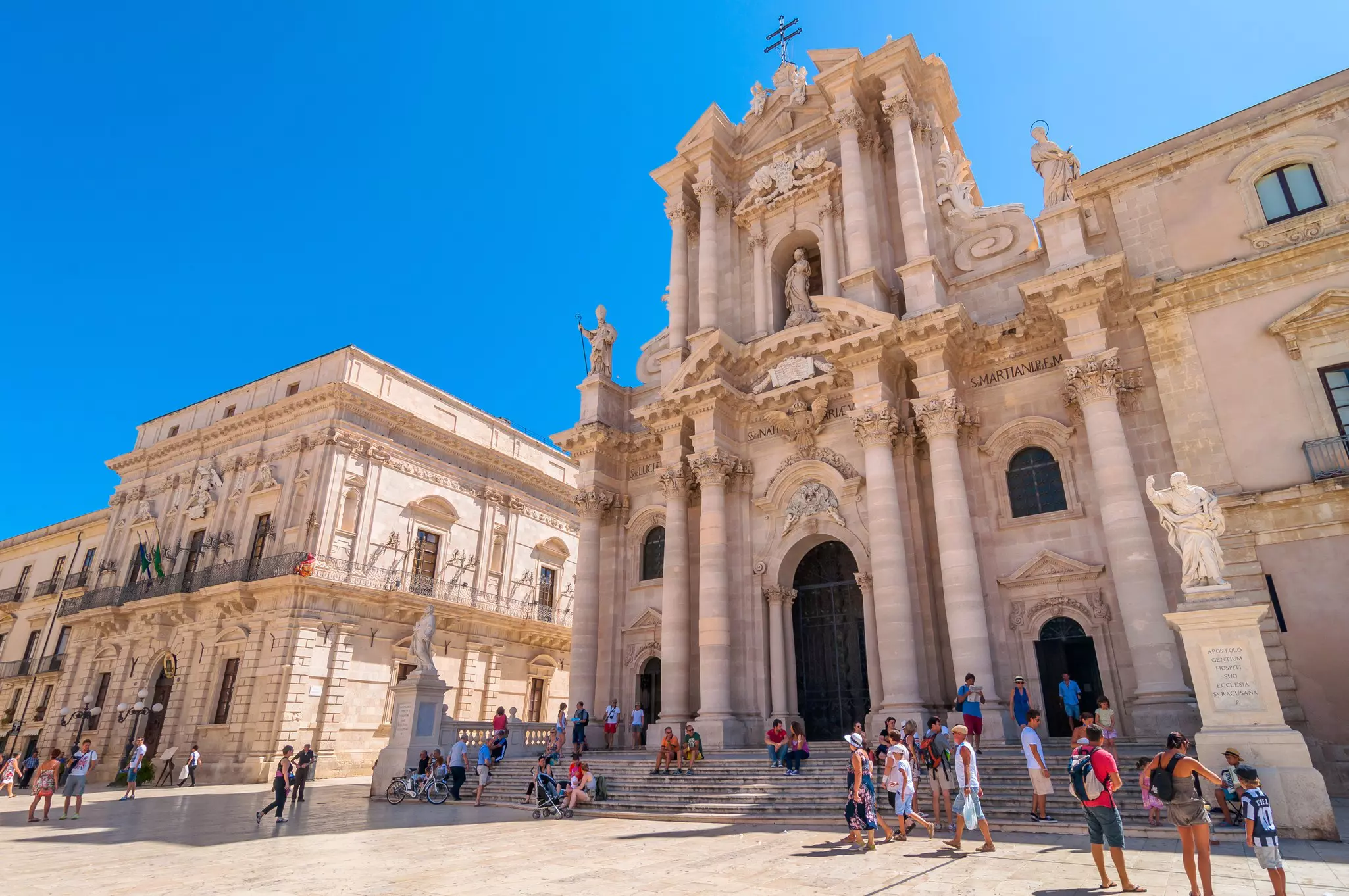 Visitors explore the Piazza del Duomo in front of the city's cathedral in Ortygia, Syracuse, Sicily.