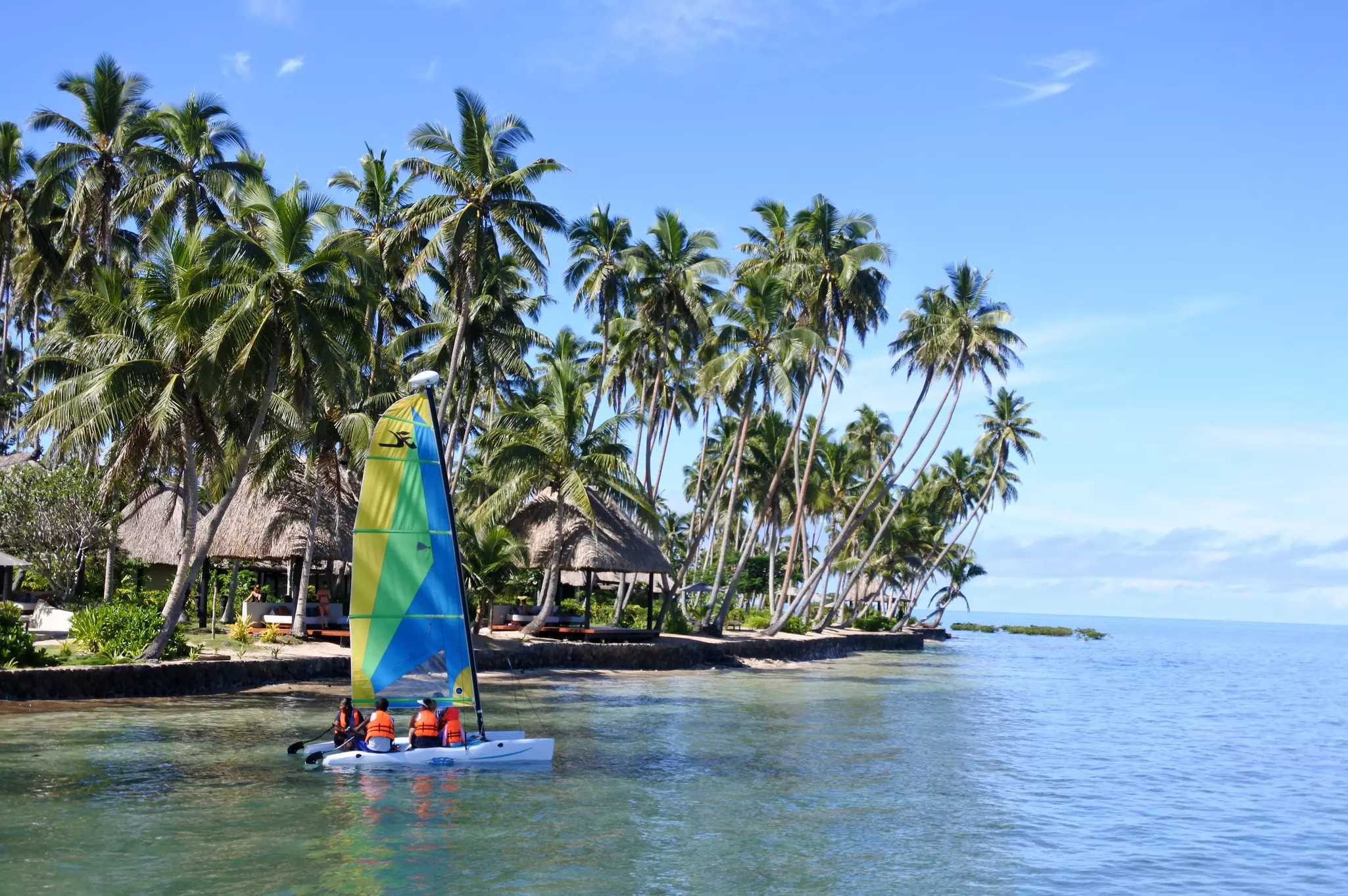 Catamaran sailboat crew sailing along tropical landscape of a luxurious resort on Vanua Levu Island, Fiji.,
