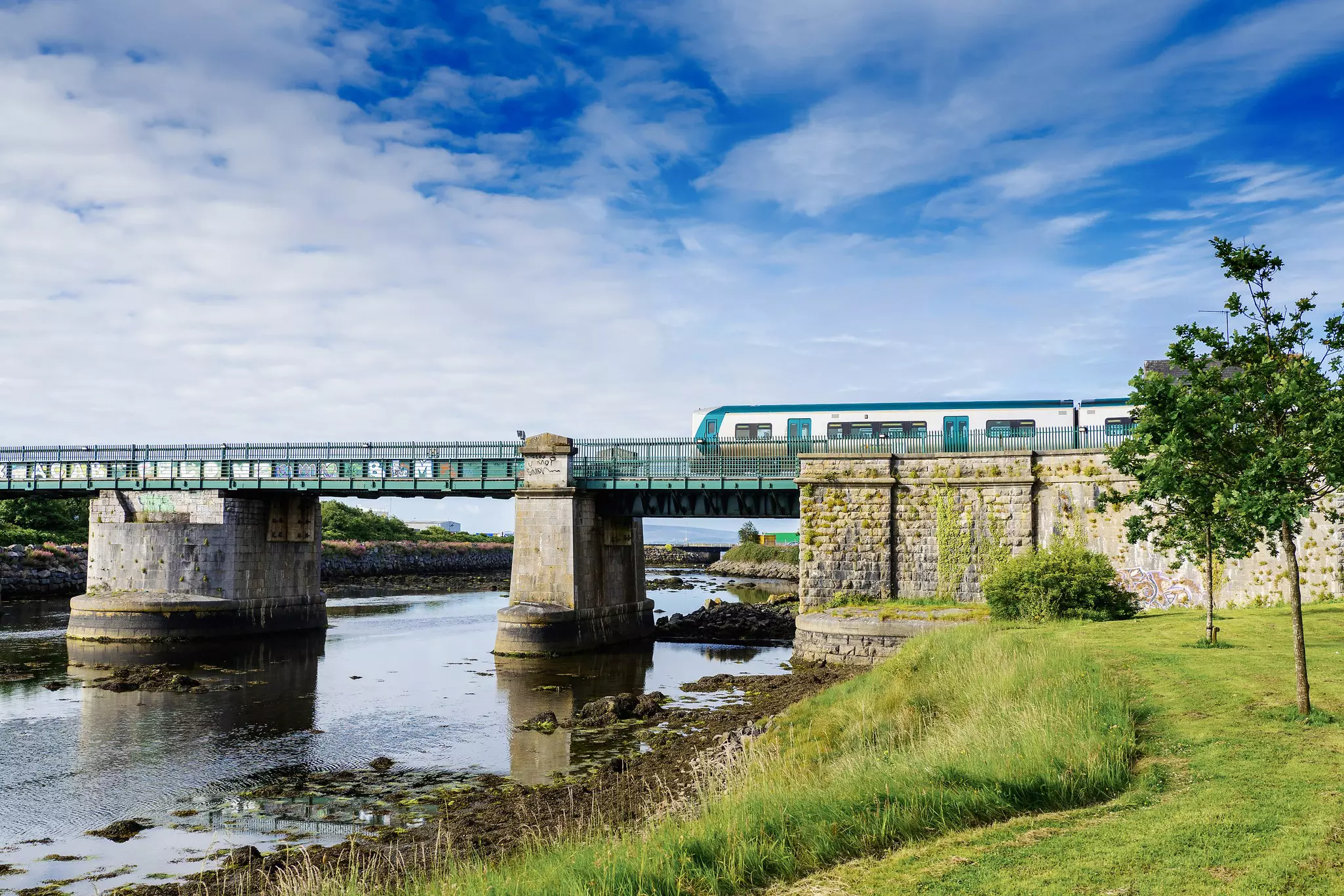 A Galway train crosses a bridge by Lough Atalia in Ireland.