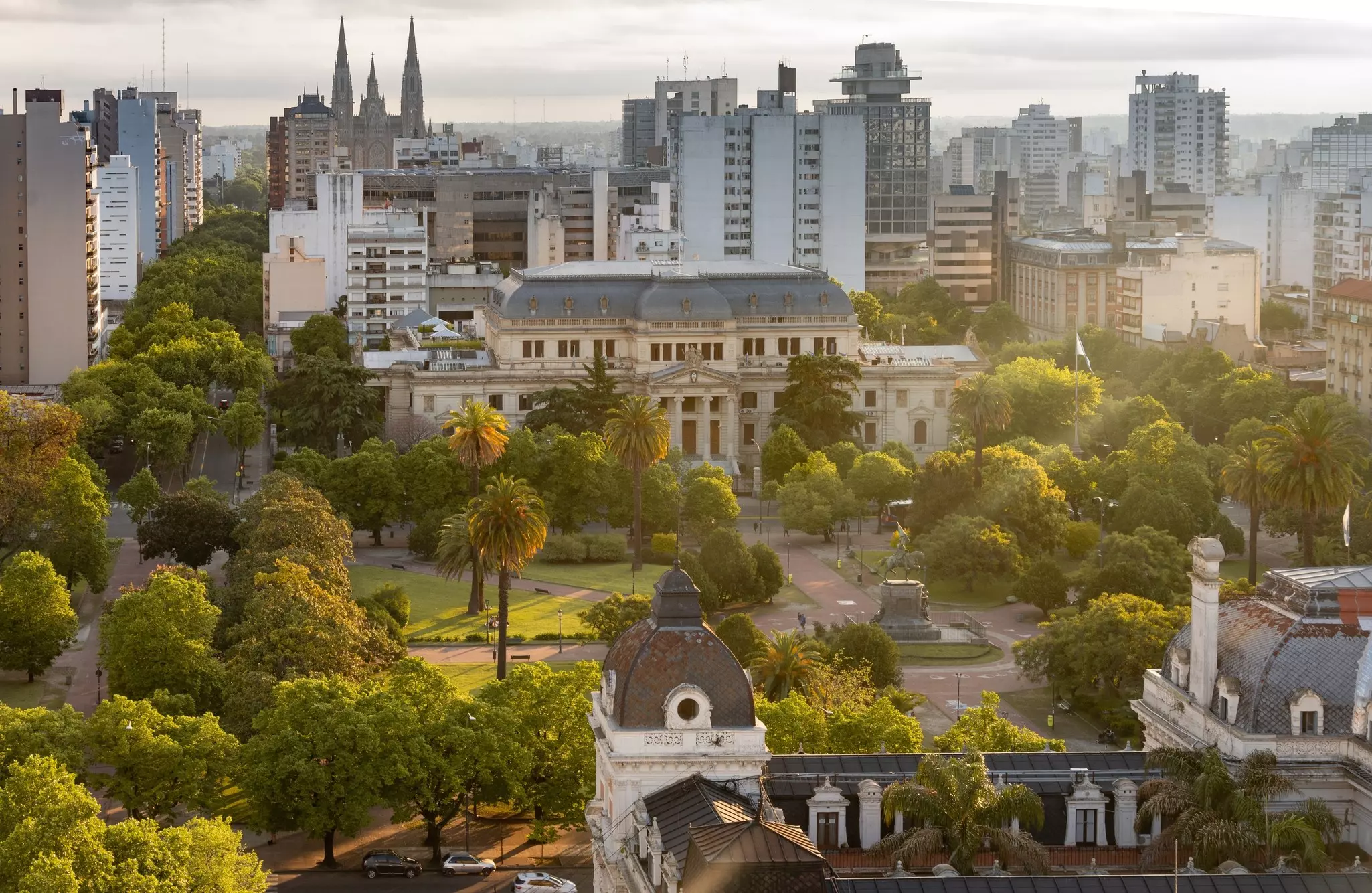 An aerial view of a city square filled with trees and surrounded by grand buildings.