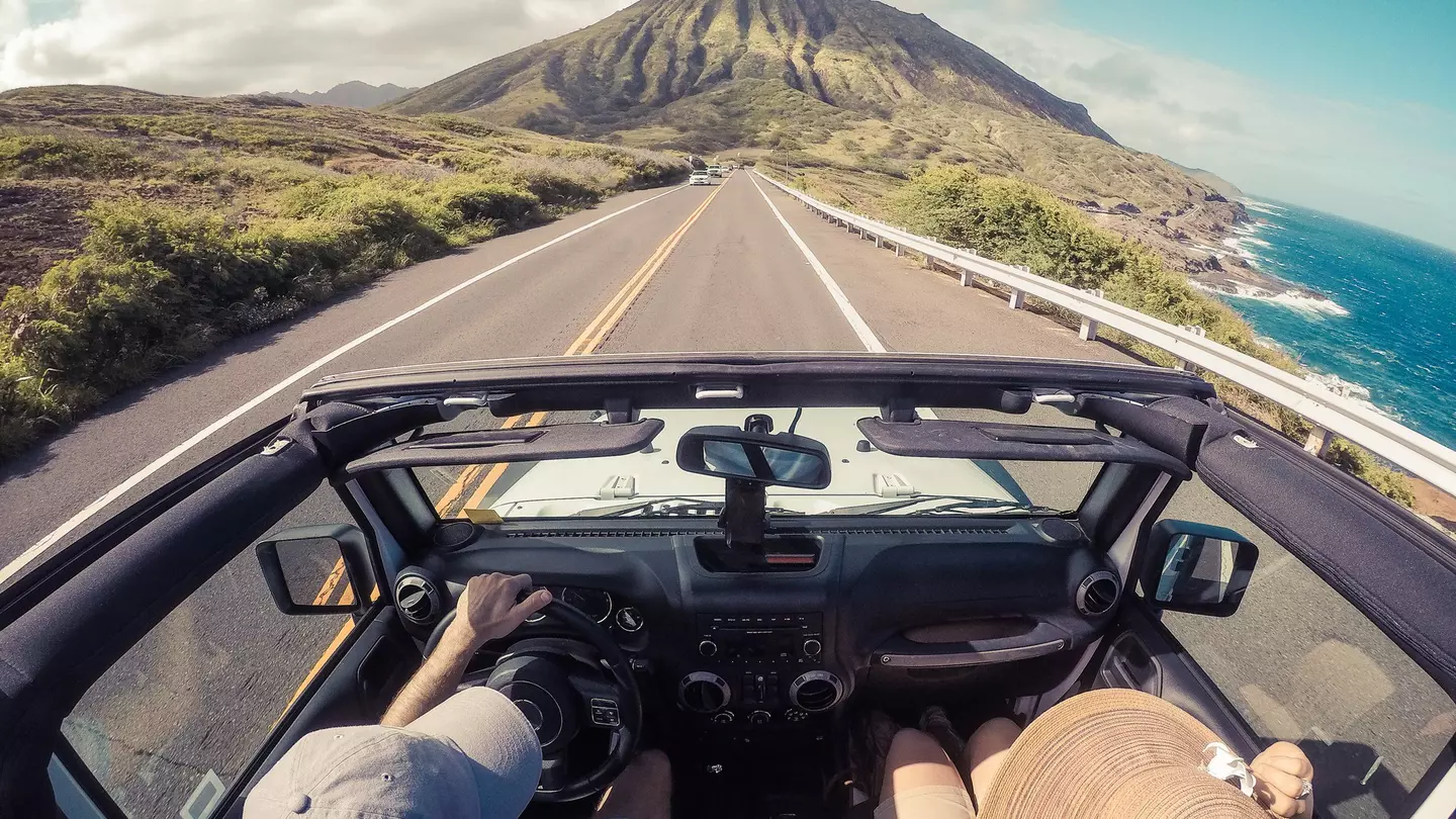 Rear view of a couple driving in a convertible along a coastal road
