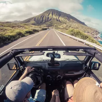 Rear view of a couple driving in a convertible along a coastal road