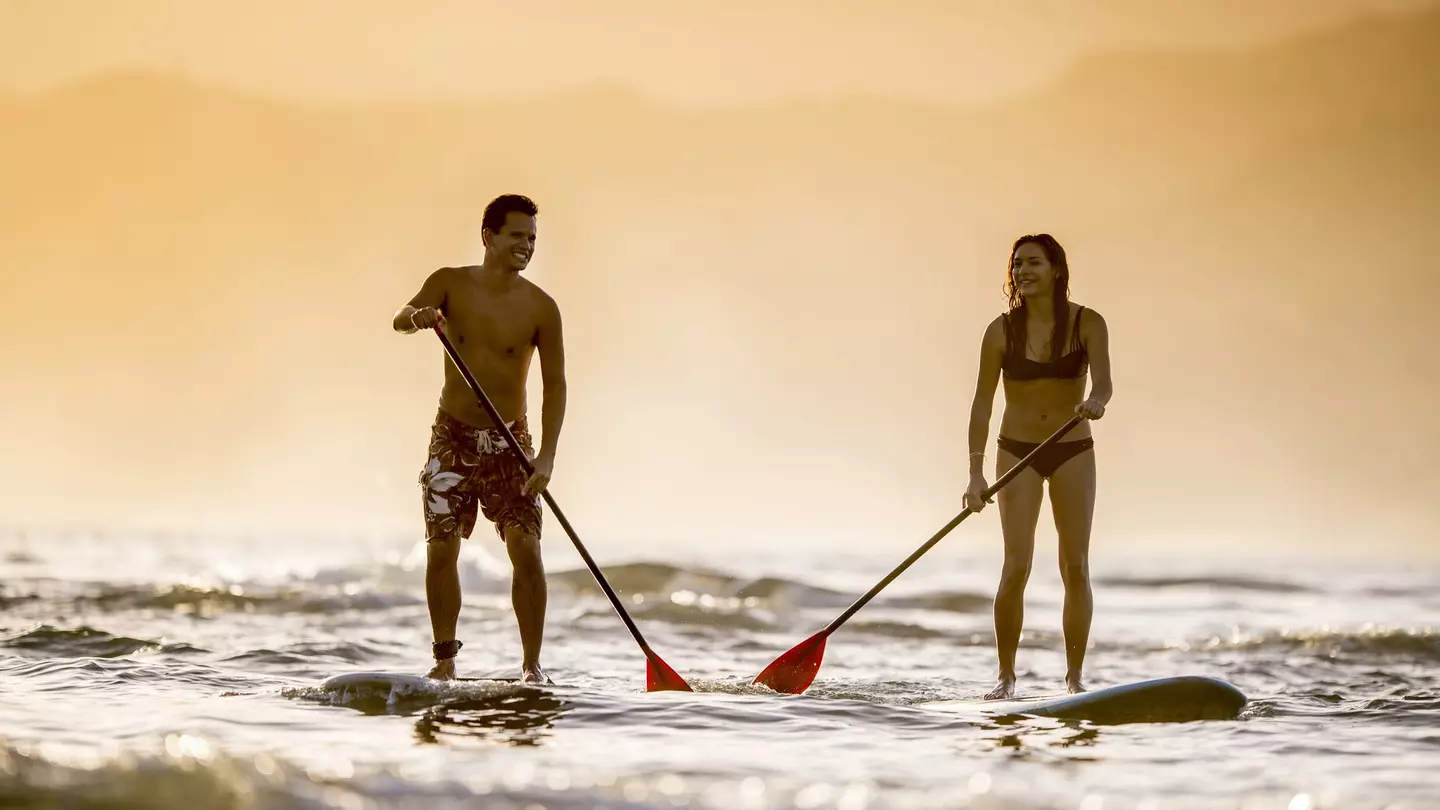 Couple stand up paddleboarding off Kaua'i