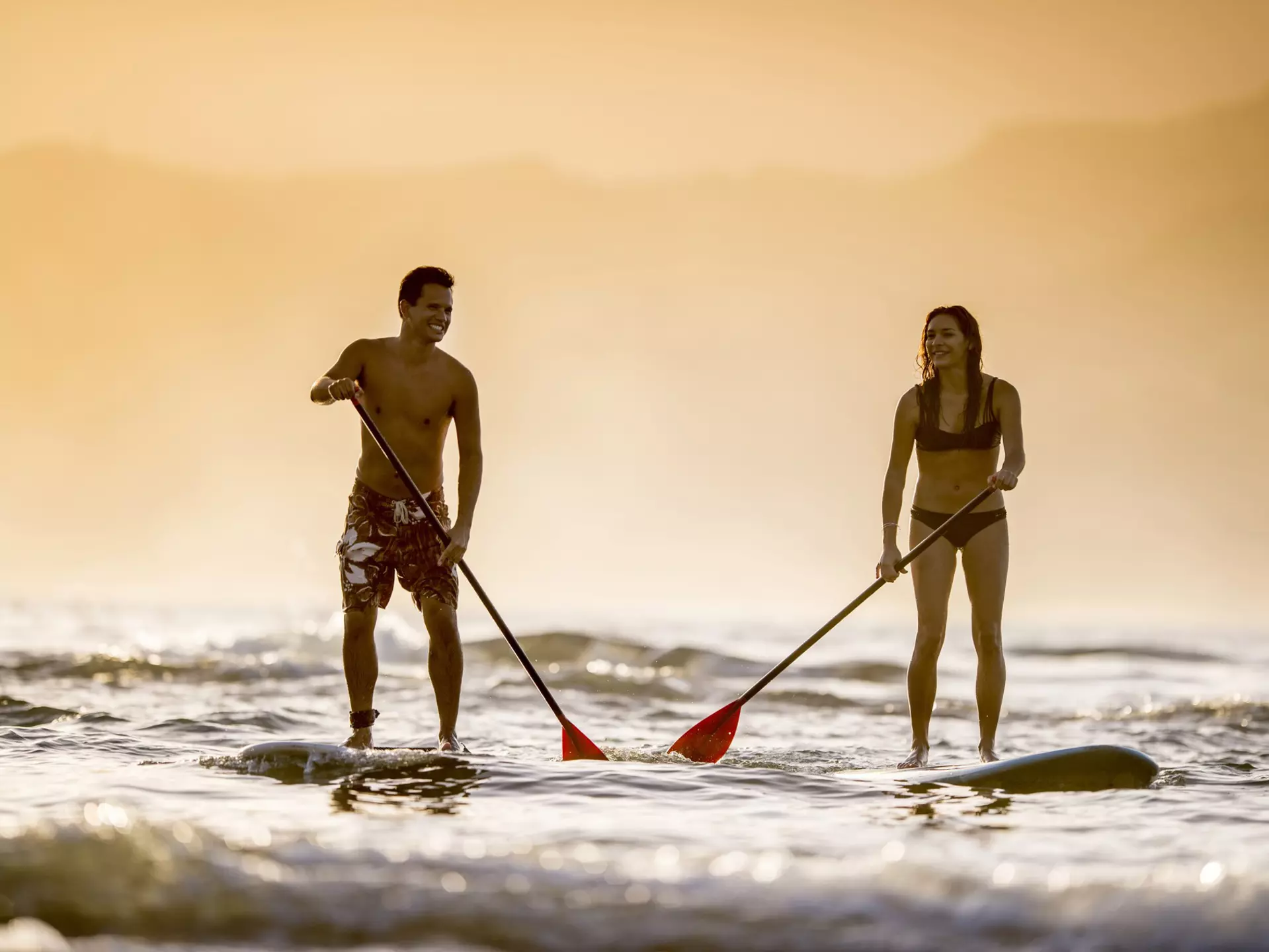 Couple stand up paddleboarding off Kaua'i