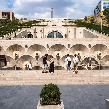 Travertine stairway terraces with fan-shaped fountains at the Cascade in Yerevan, Armenia, climbing a green hillside