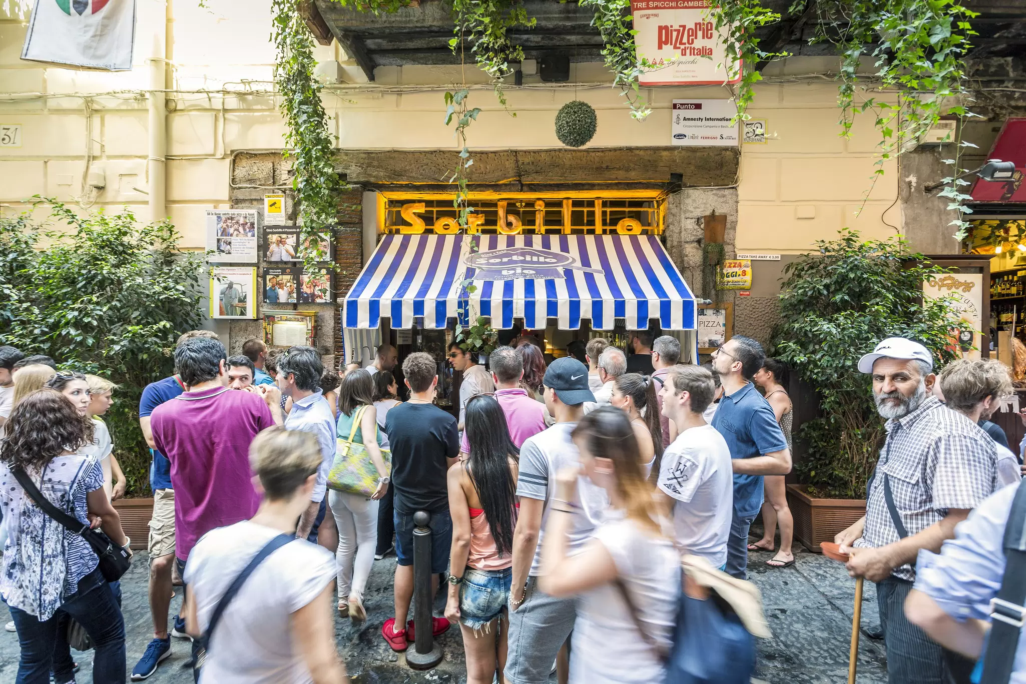 People crowded outside a storefront with blue and white awning that says "Sorbillo"