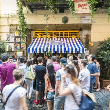 People crowded outside a storefront with blue and white awning that says "Sorbillo"