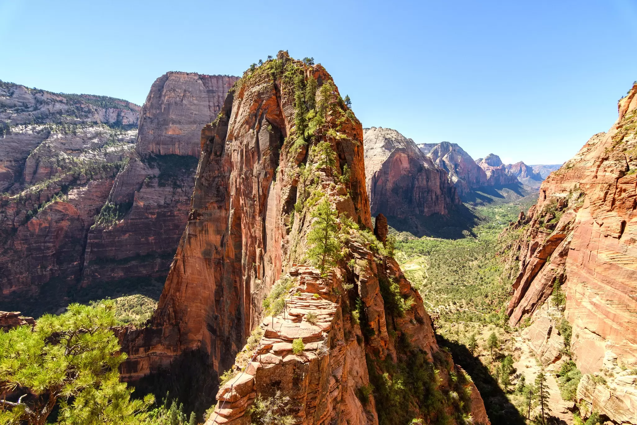 A huge red-rcok outcrop stands high above a river valley: Angels Landing in Zion National Park, Utah.