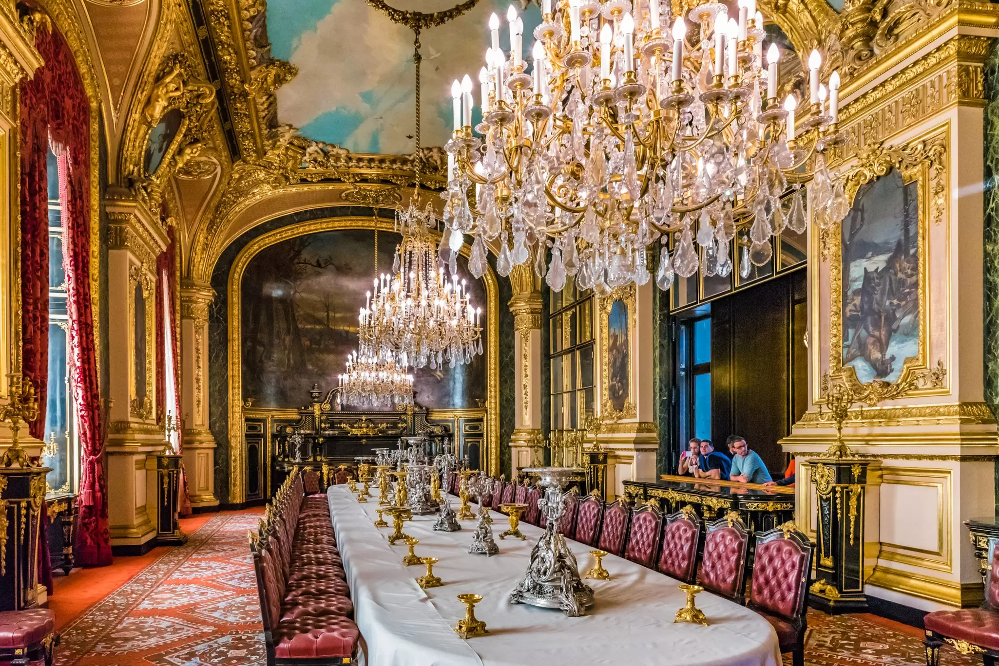 Visitors look upon the Apartments of Napoleon III large dining room exhibit inside the Louvre Museum.