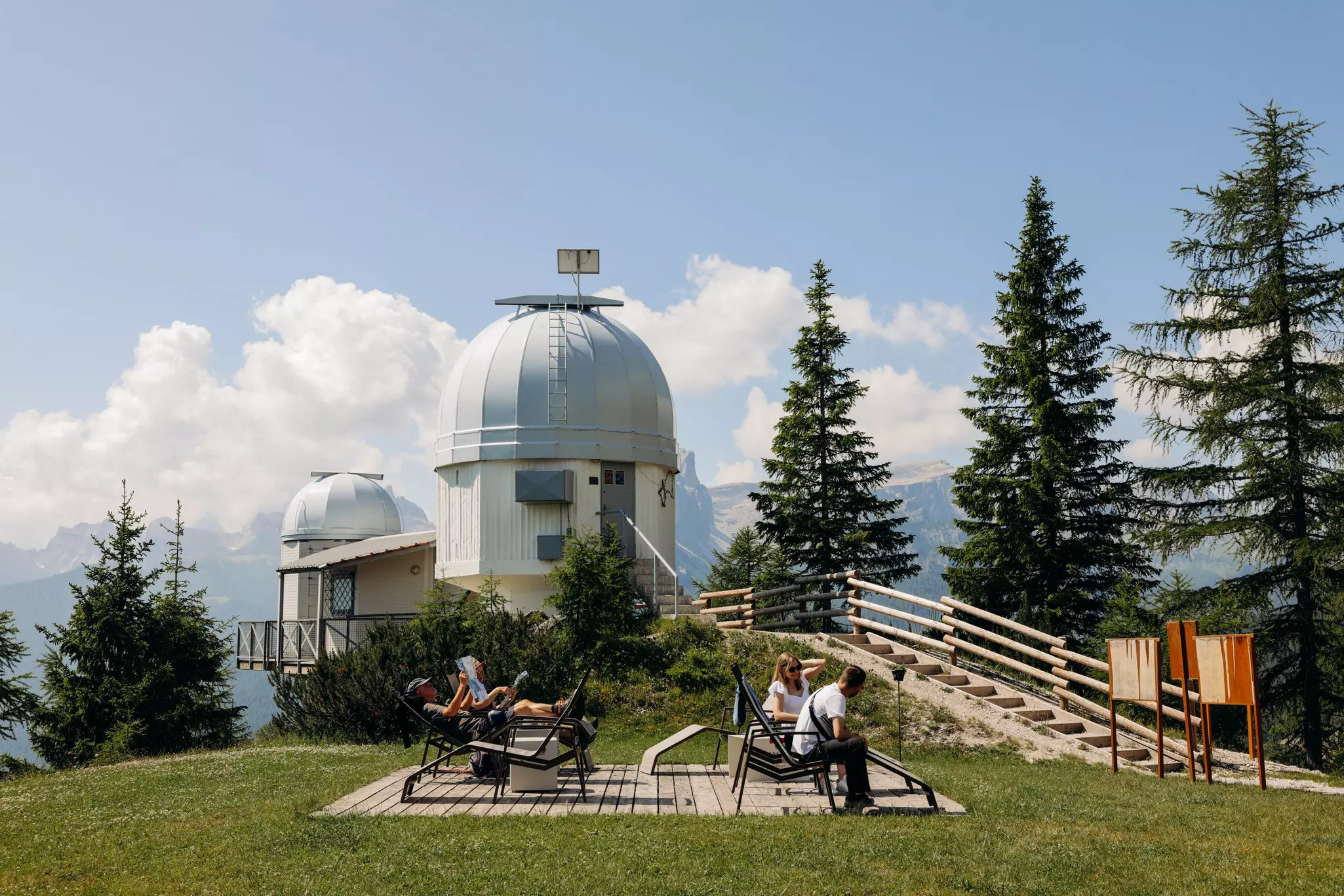People enjoy the sun with a view of the Observatory in Cortina d'Ampezzo, Italy