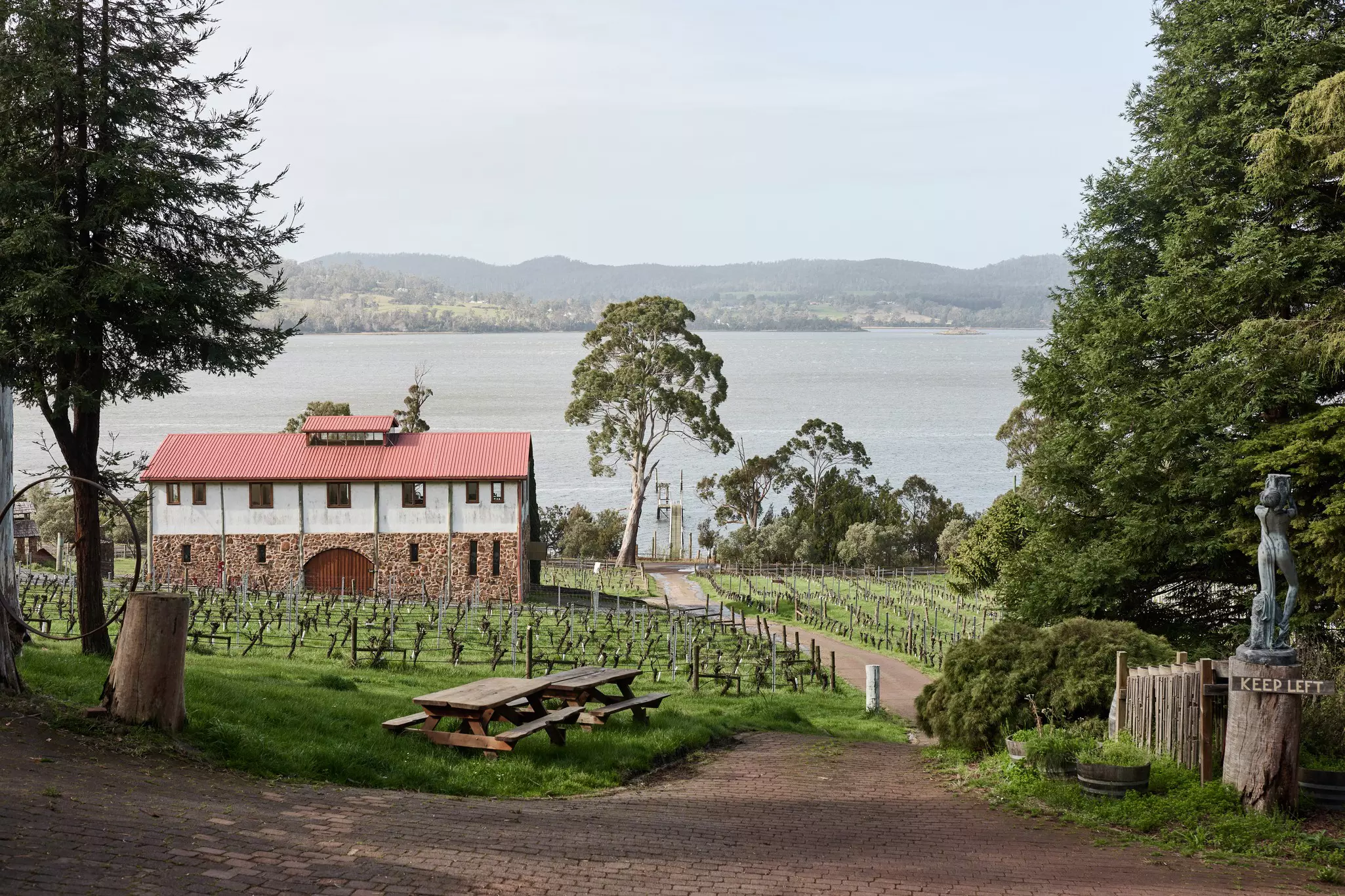 A lakeside vineyard and winery with picnic benches.