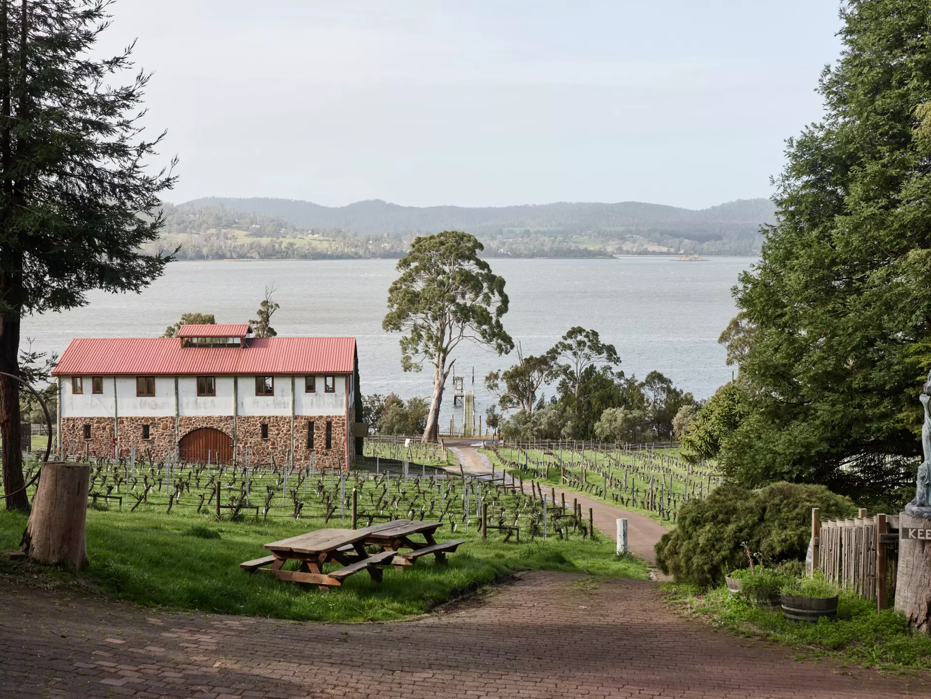 A lakeside vineyard and winery with picnic benches.