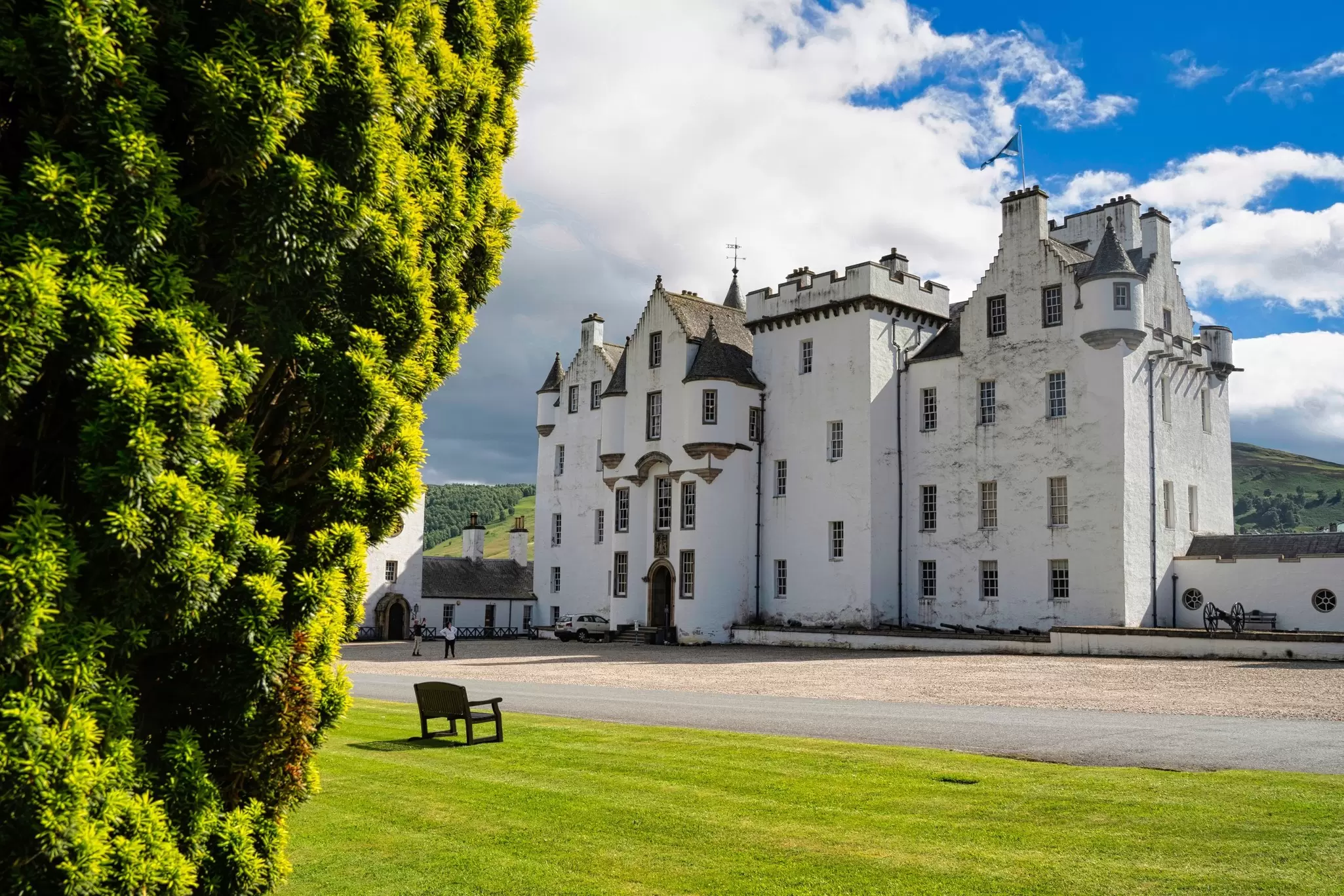 The whitewashed Castle of Blair Atholl in summer with a blue sky and green grass.