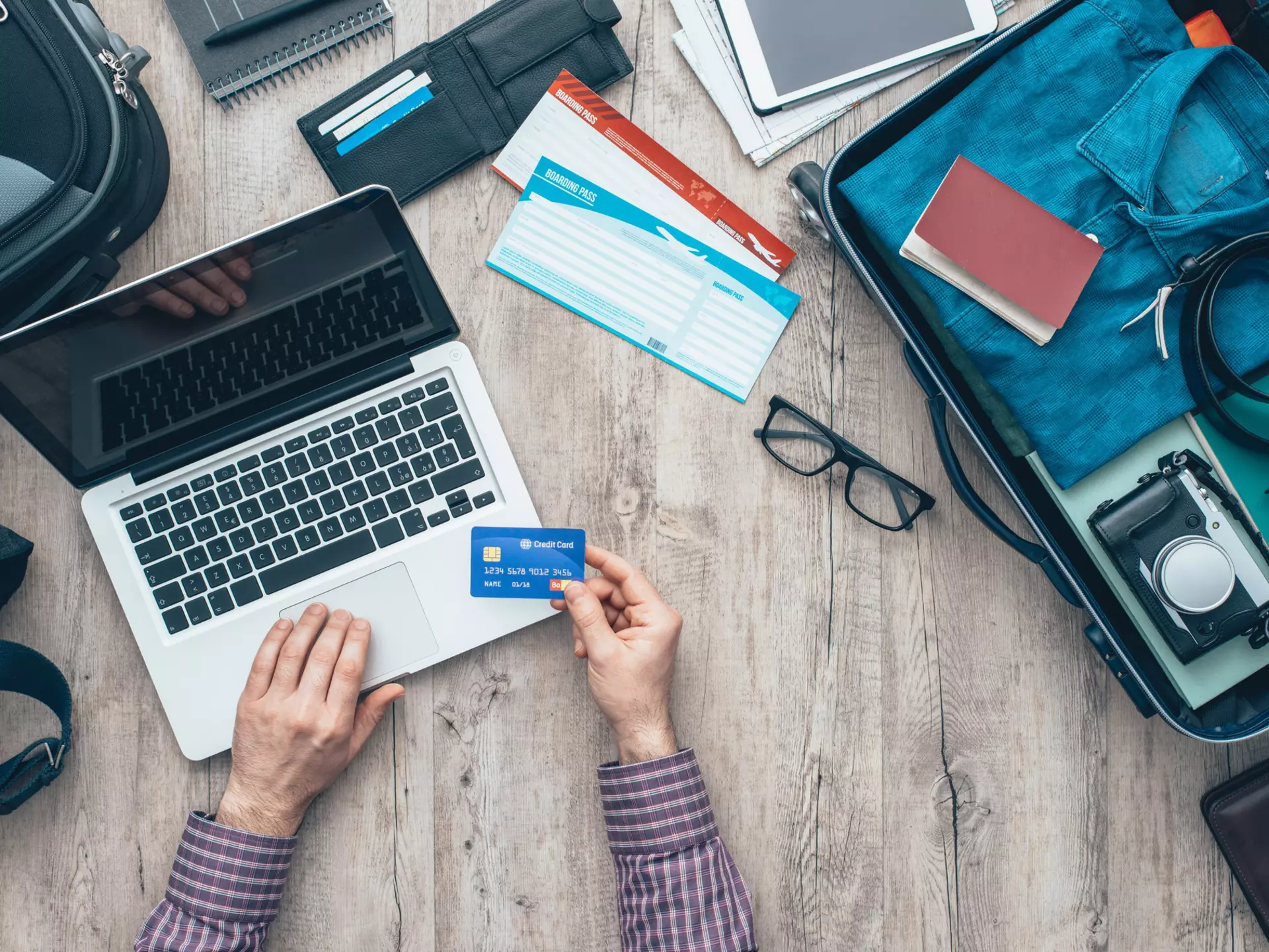 Traveler getting ready for a trip, he is packing his bag and booking a flight online using a credit card and a laptop, flat lay  License Type: media  Download Time: 2023-04-28T13:53:26.000Z  User:   Is Editorial: No  purchase_order:   