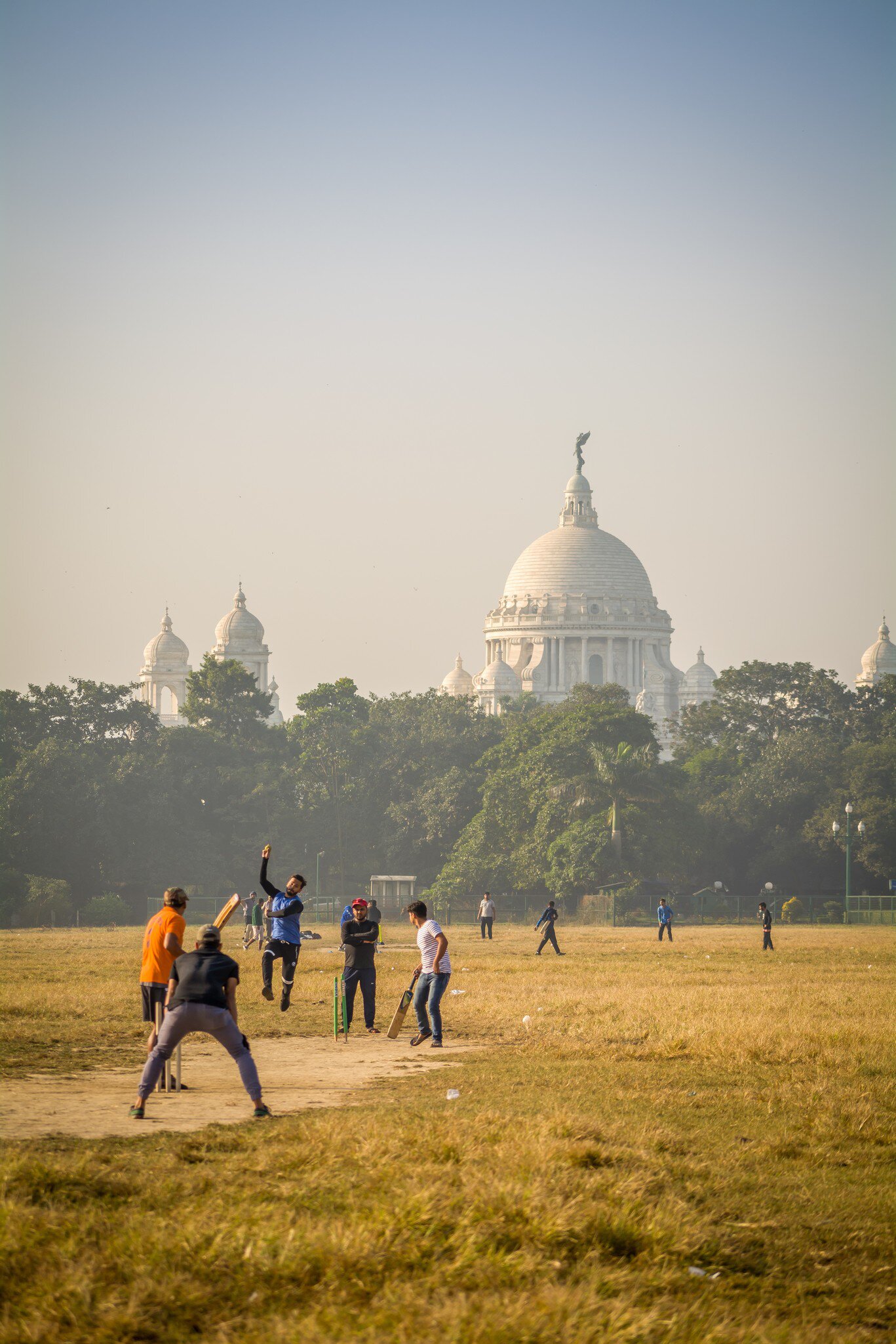 A cricket match in Maidan with the Victoria Memorial in the distance. Kolkata, West Bengal, India.