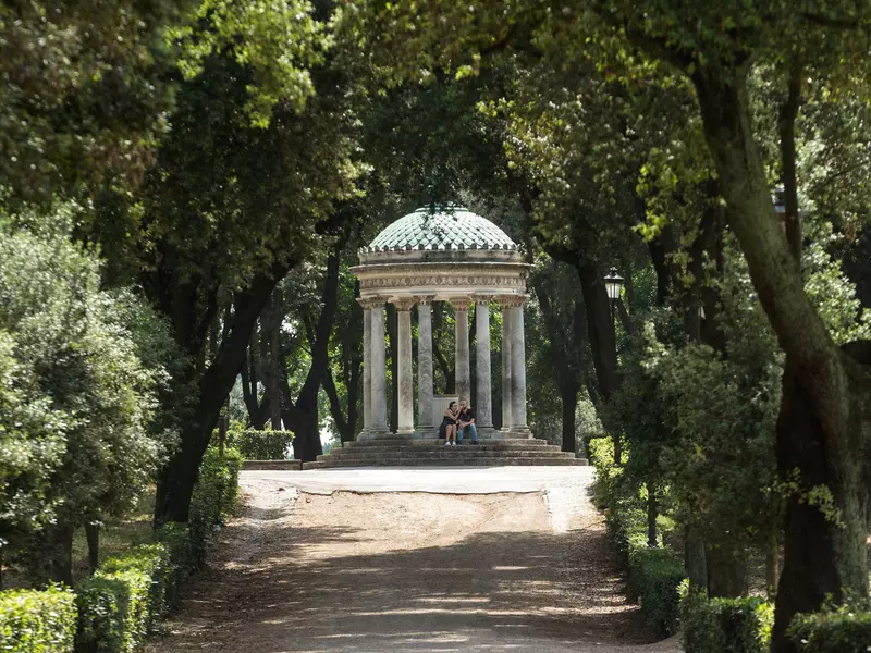 A neoclassical structure with eight Corinthian columns, surrounded by lush greenery.