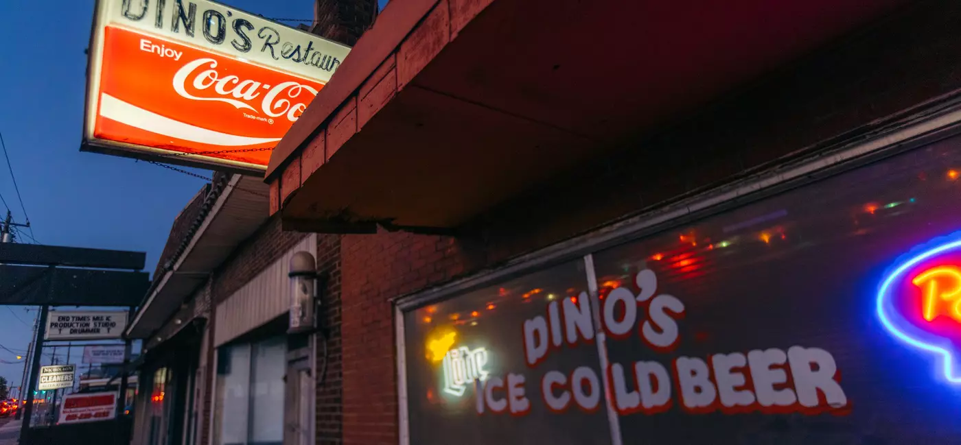Exterior of Dino's dive bar with a vintage coca cola stand