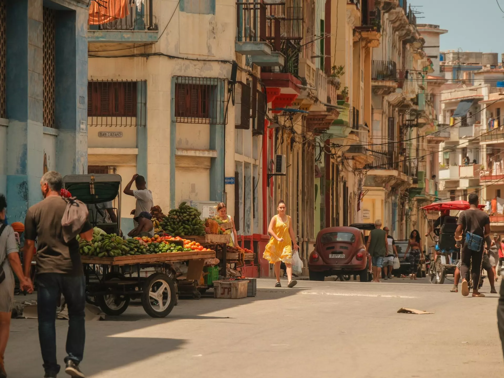 People walking on the streets in Havana, with vendors selling fruits in carts