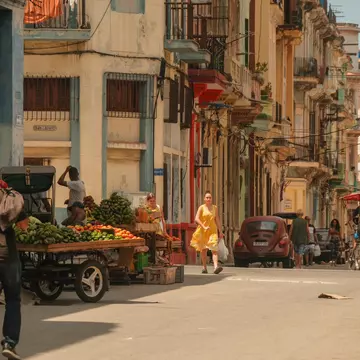 People walking on the streets in Havana, with vendors selling fruits in carts