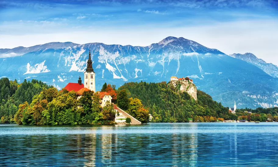 Lake Bled in Slovenia, with the island church and clifftop Bled Castle below the Julian Alps in autumn colour