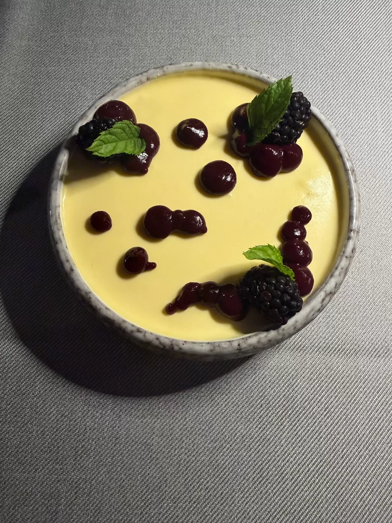 Closeup up of a bowl of lavender tiramisu topped with blackberries. 