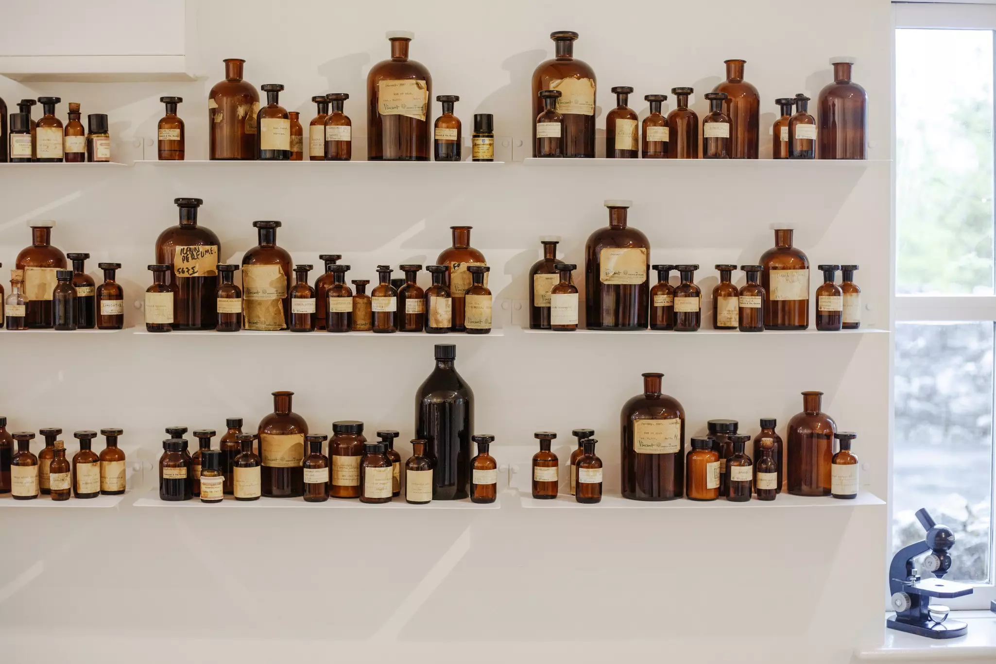 Glass bottles of various sizes sit on shelves against a white wall at a boutique.