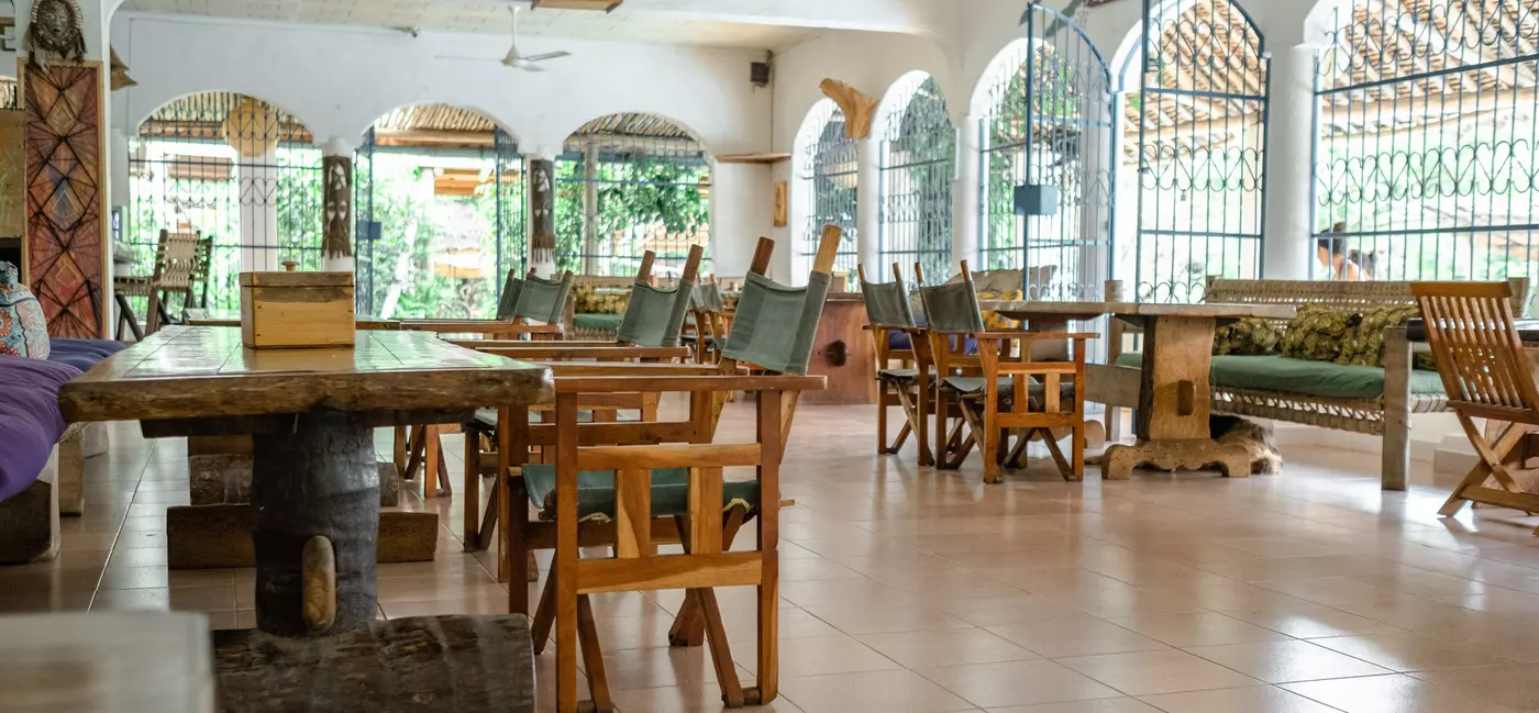 A spacious dining room with chairs and benches at wooden tables.