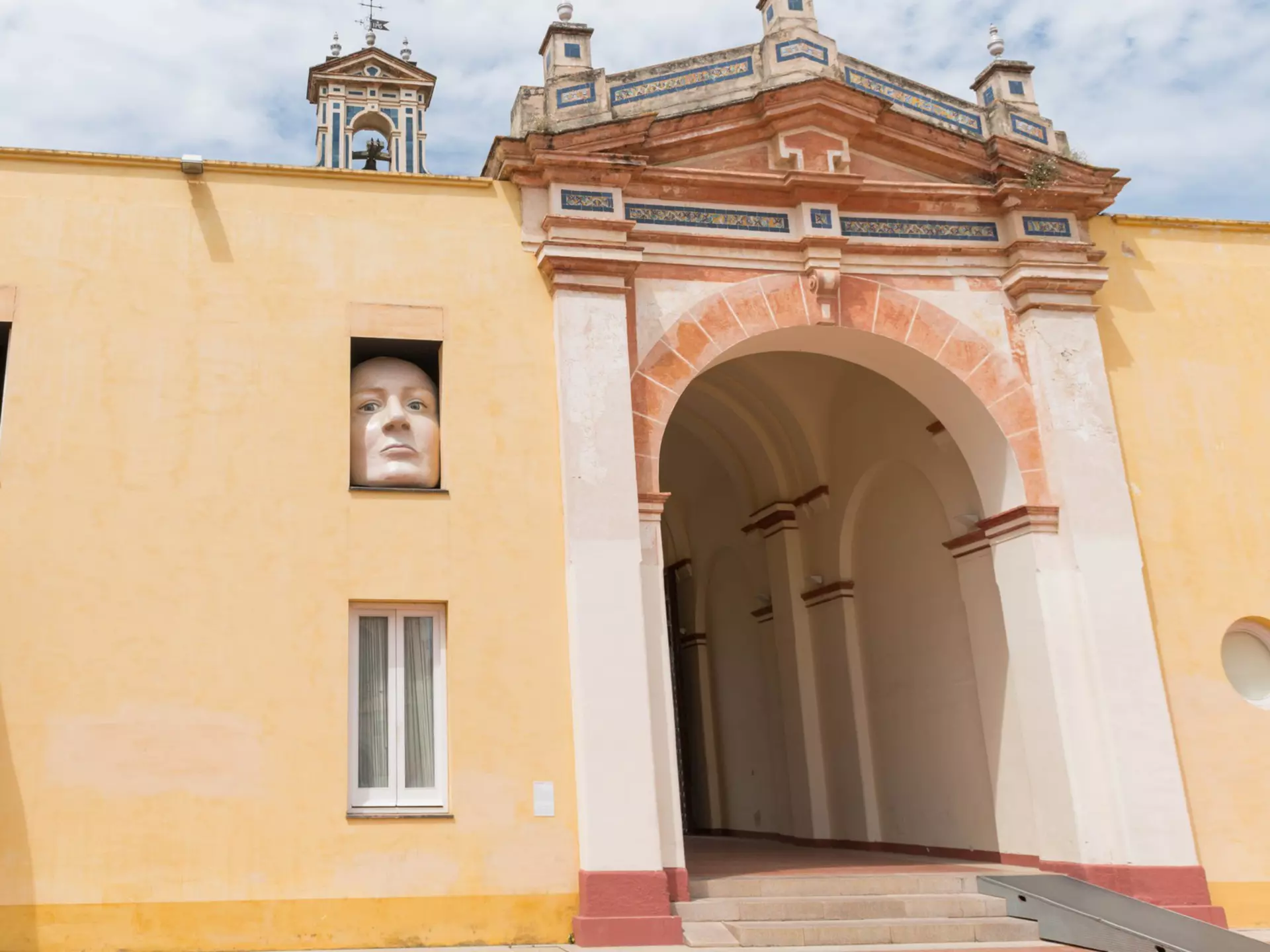 A huge sculpture of a face and an arm reach out of a building