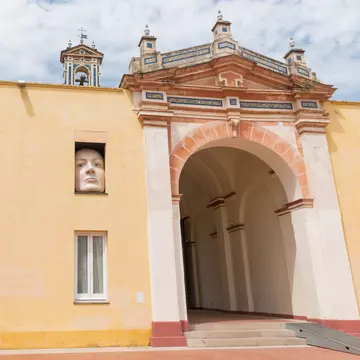 A huge sculpture of a face and an arm reach out of a building