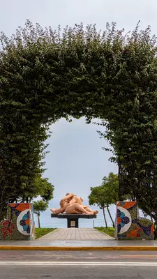 A trimmed hedge frames a sculpture against the sea in Lima, Peru.