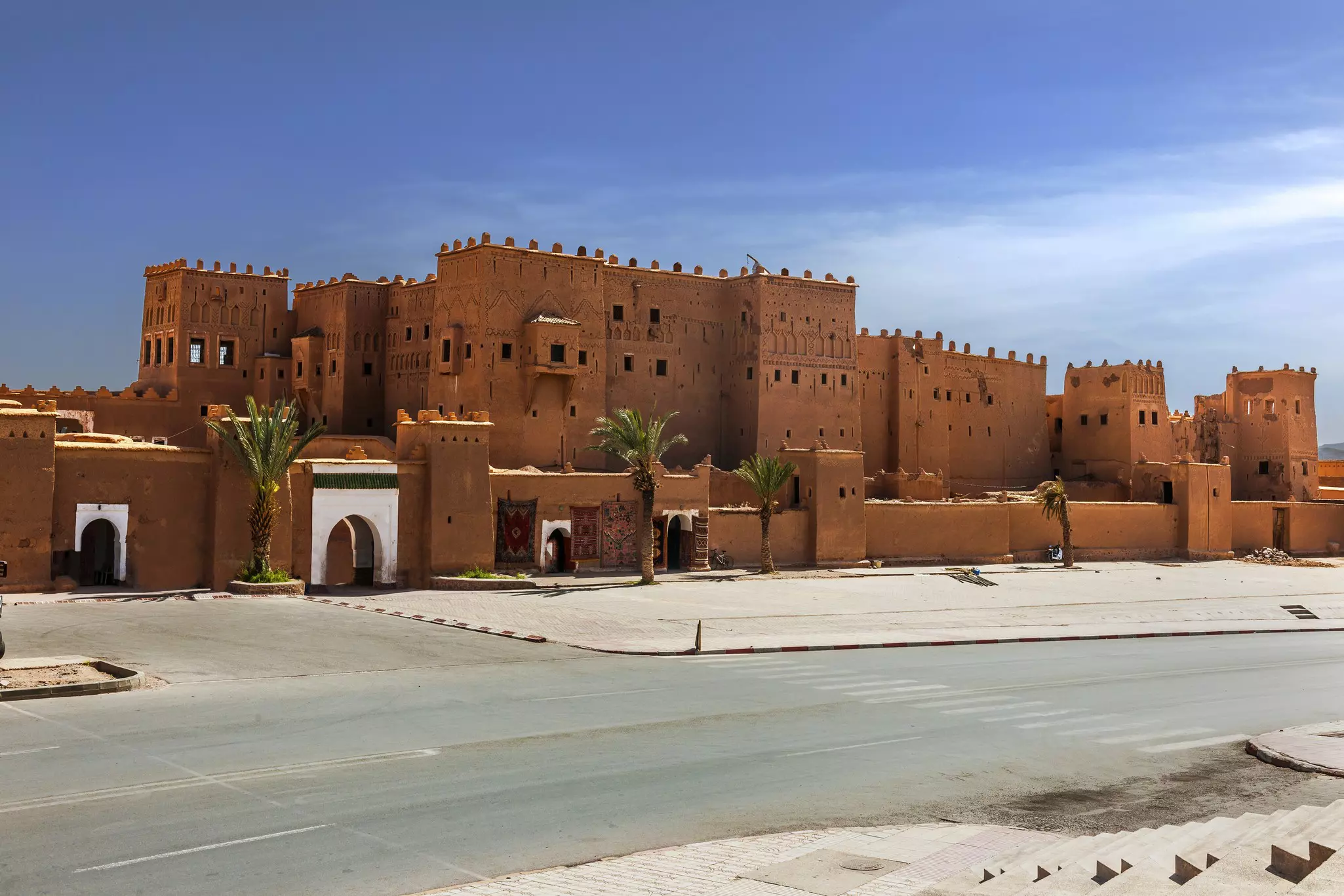 A red building with turrets on top and four palm trees