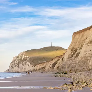 A beach backed by cliffs topped with a monument