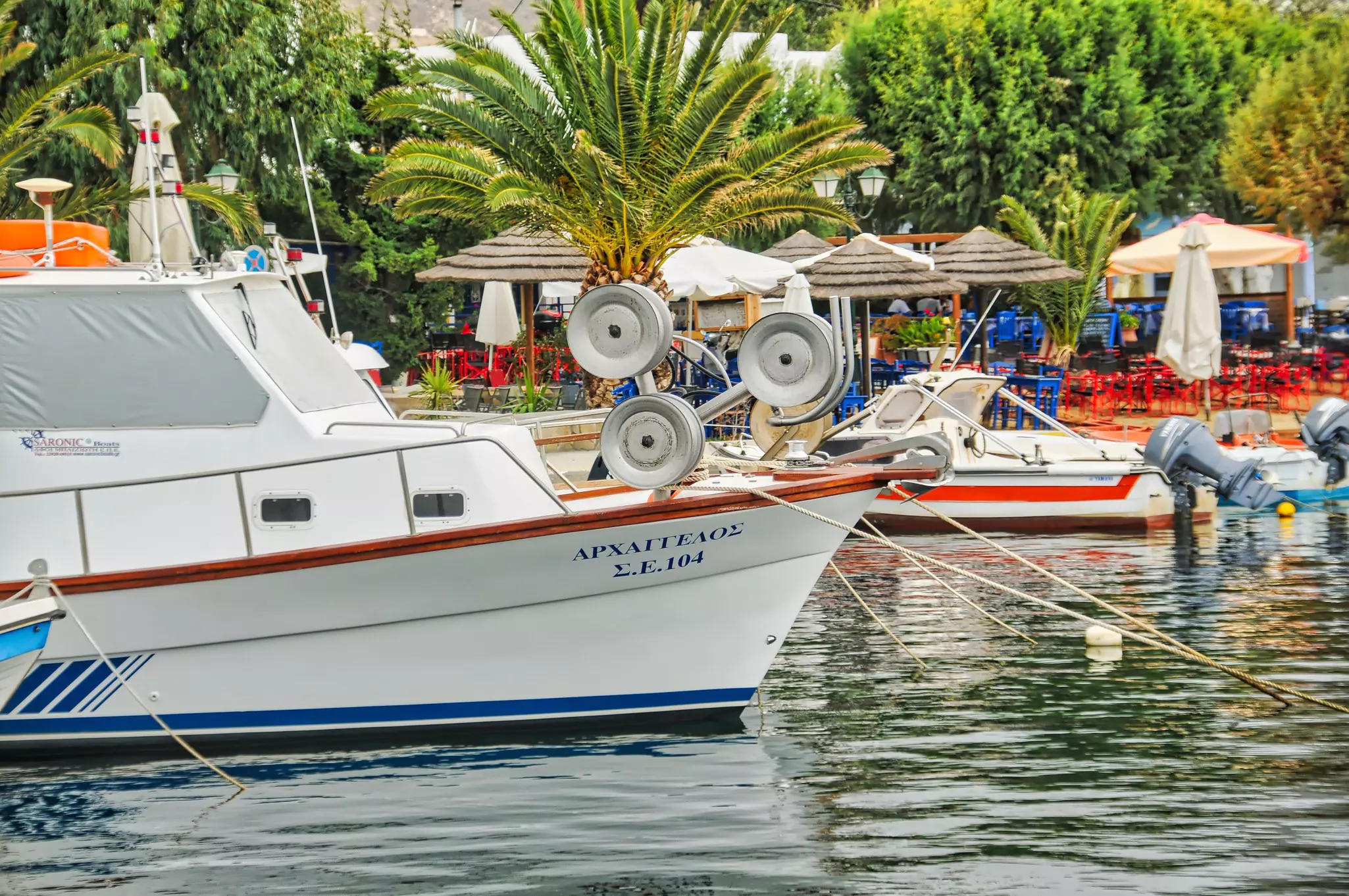 Fishing boats by the dock in Livadi village, Serifos island, on a sunny day with a blue sky.
