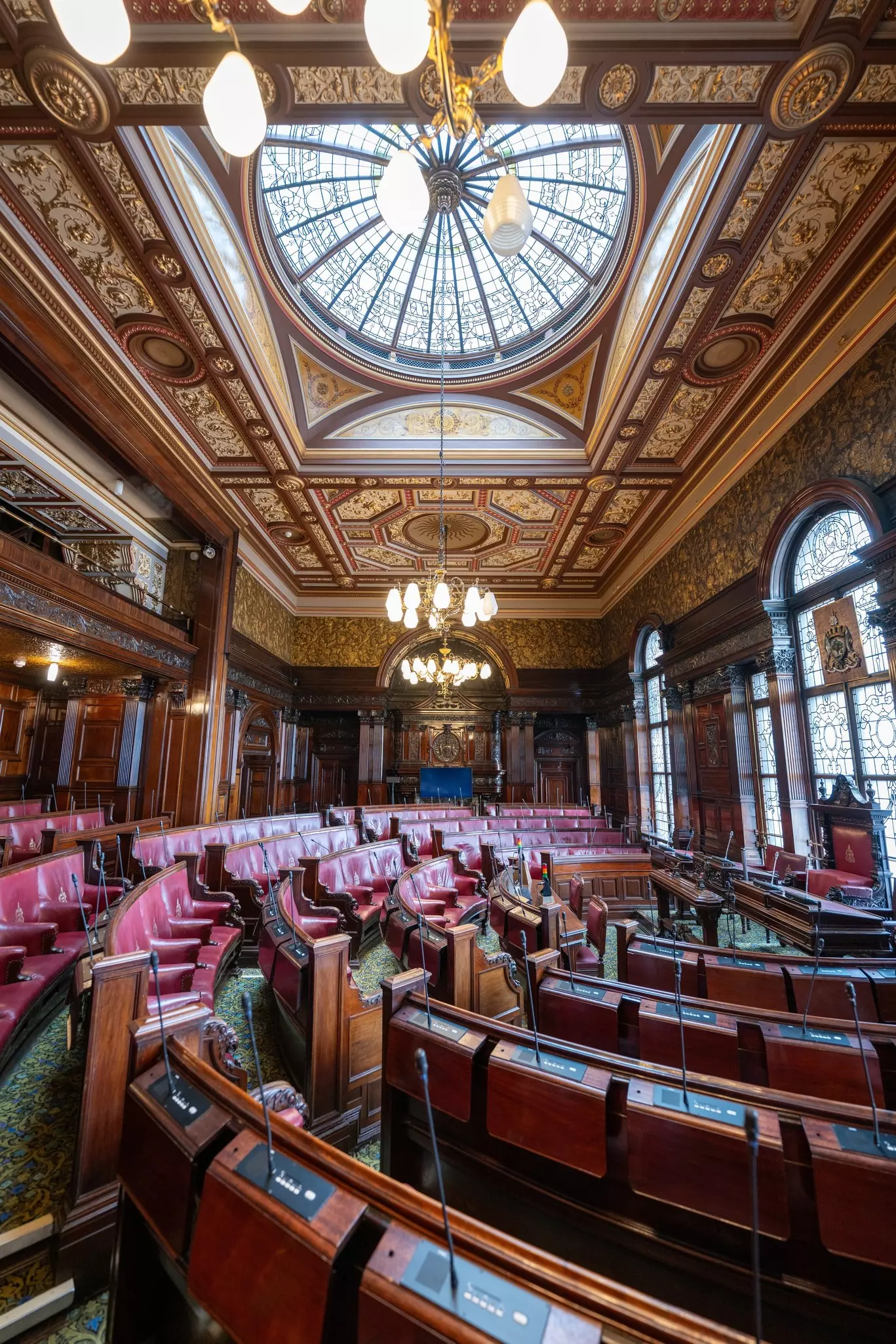The Council Chambers, lined with mahogany and red leather chairs, inside the Glasgow City Chambers building.