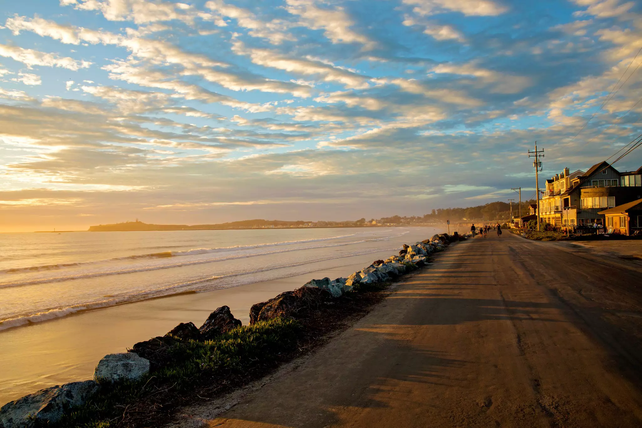 A view of Half Moon Bay with a golden reflection on the water, and the shadows of rocks on the sand