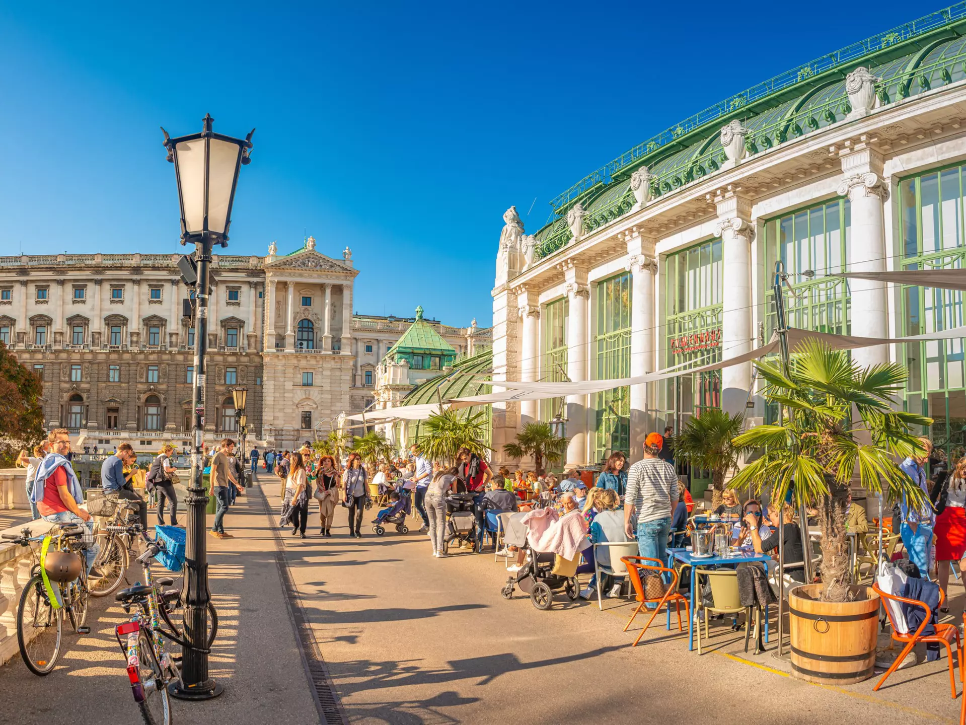 People enjoying the sunshine near the Imperial Butterfly House at the edge of the Burggarten park.