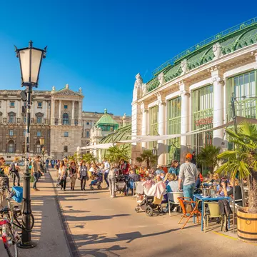 People enjoying the sunshine near the Imperial Butterfly House at the edge of the Burggarten park.