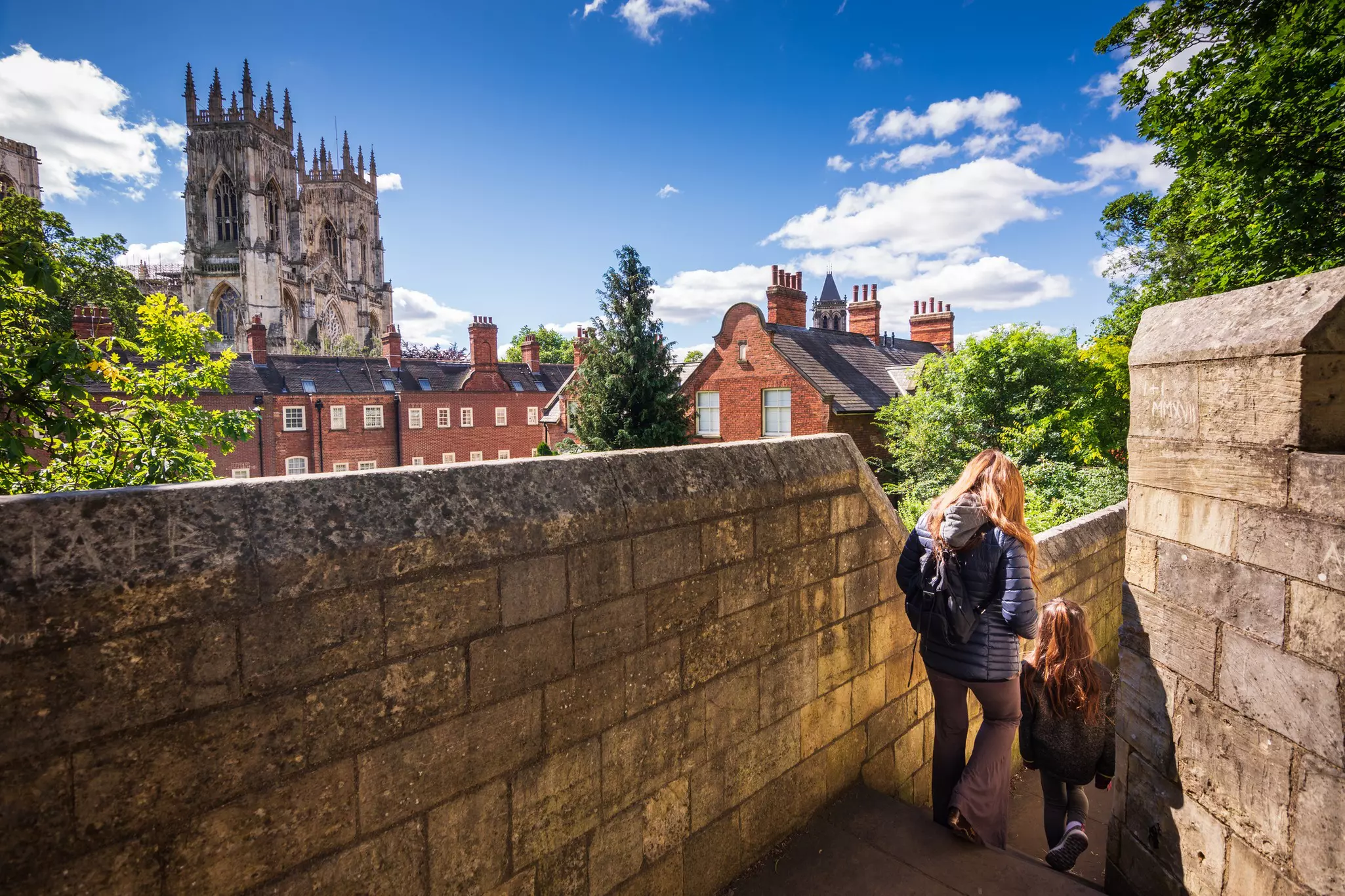 The mother and daughter exploring the walls as they walk around the city of York. In the background, the grand York Minster can be seen.