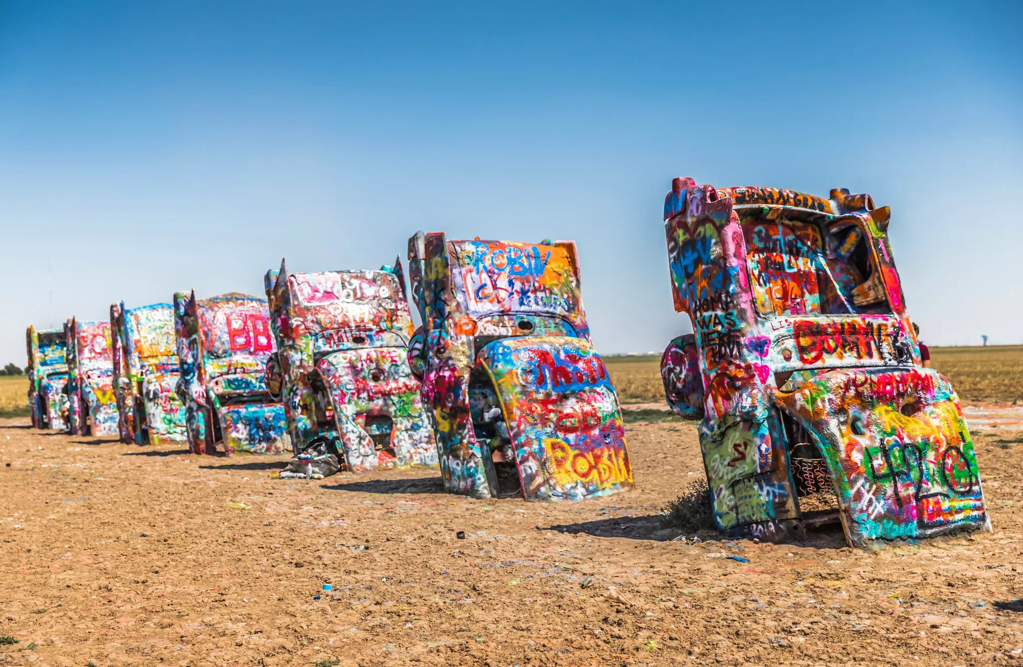 Brightly colored cars (though not EVs) are permanently parked at Cadillac Ranch, along historic Route 66 © YuniqueB / Shutterstock