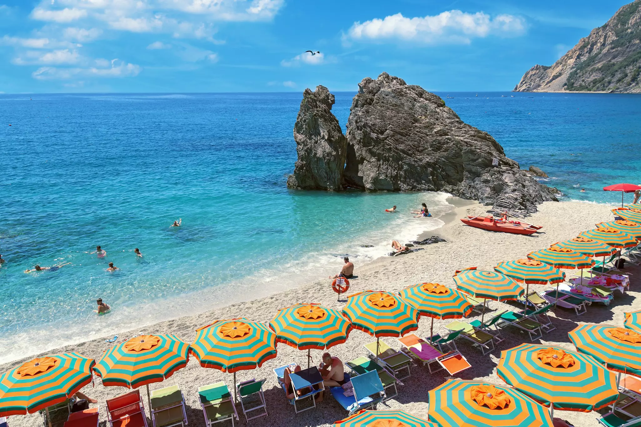 Beach at Monterosso al Mar at the Cinque Terre, Italy, lined with striped parasols and sunloungers