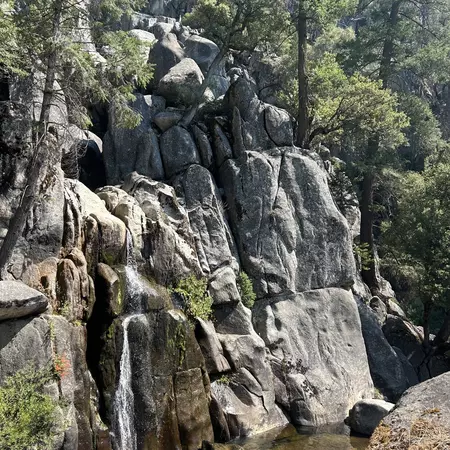 Two people sit on a rock near a waterfall in California.