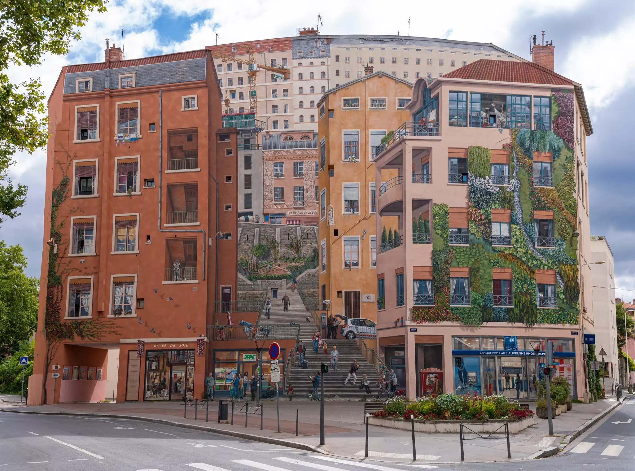 A huge trompe l’oeil mural on the exterior of a building. depicts a streetscape