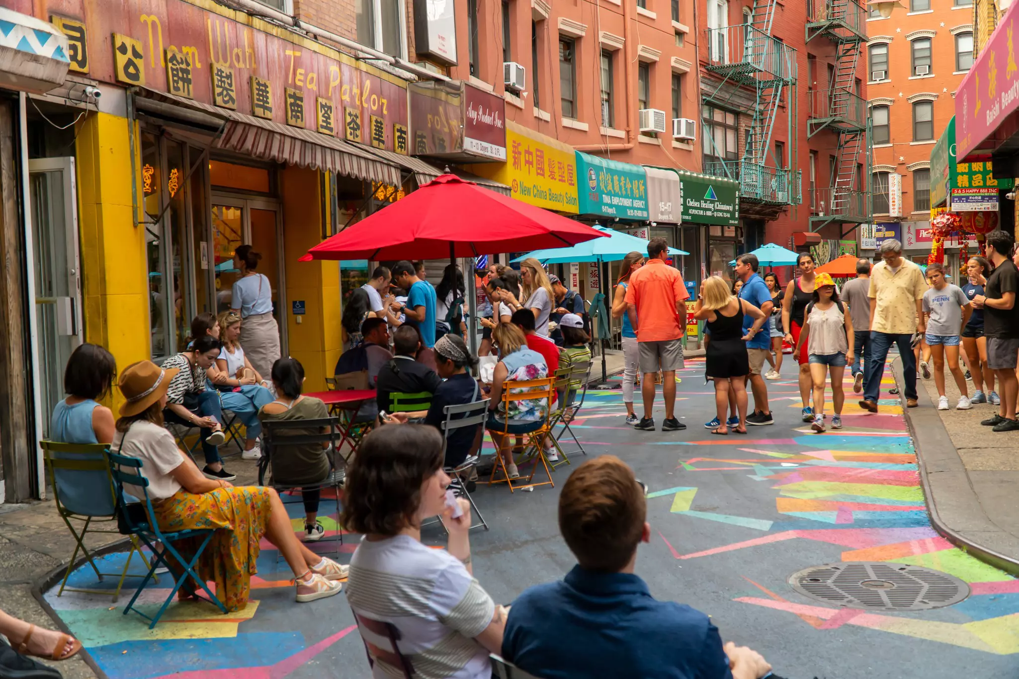 People sitting outside on Doyers Street in Chinatown enjoying tea.