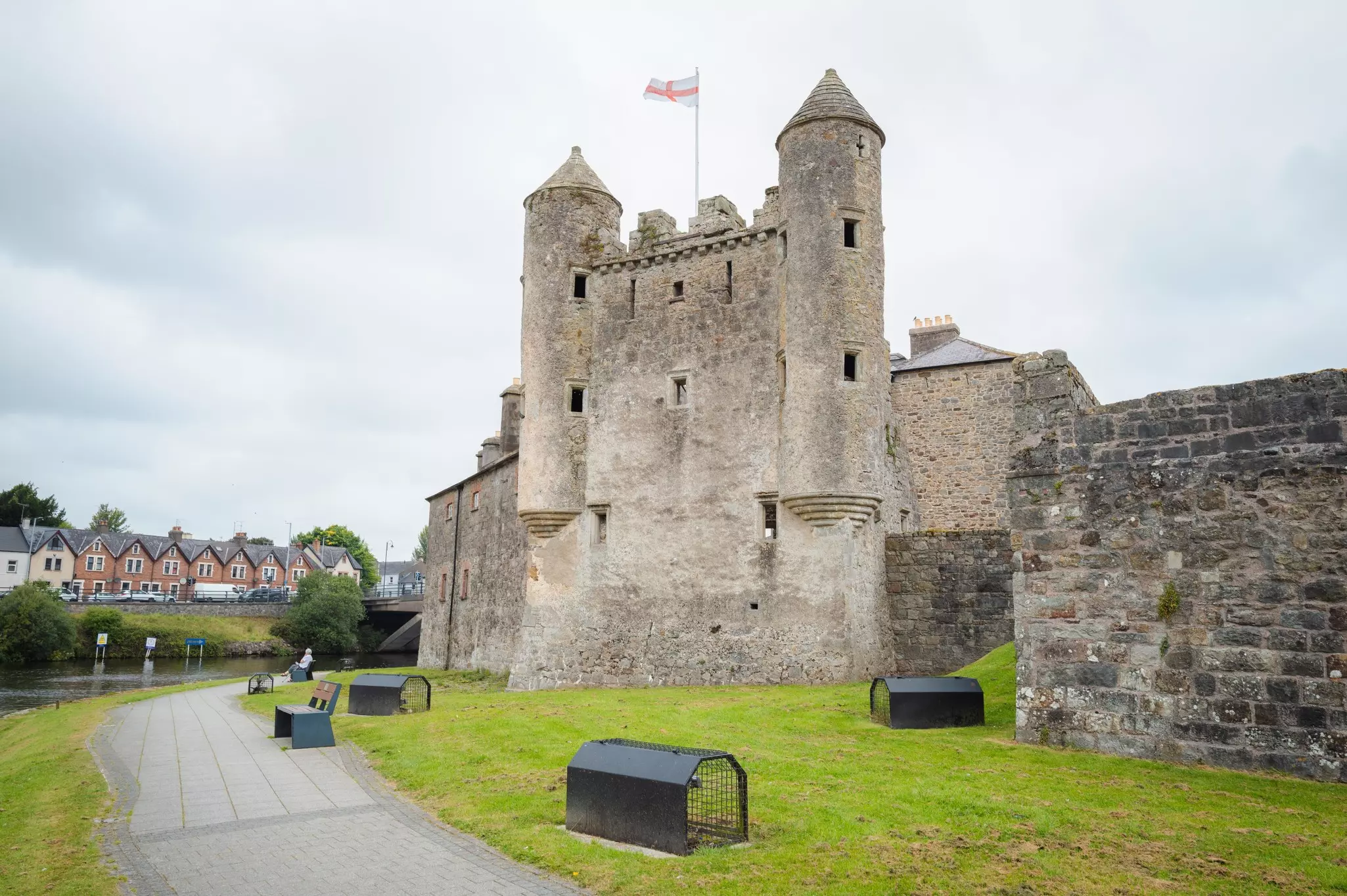 A gray castle with a stone path and closely trimmed grass around it.