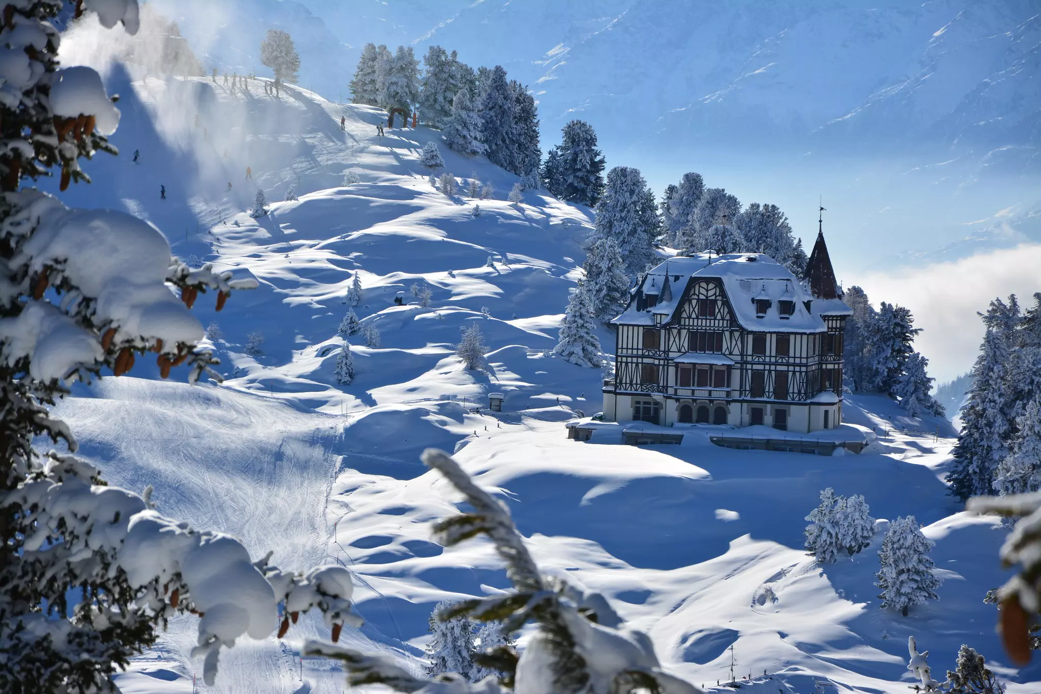 A snow-covered villa on a deep snow-covered hillside on a sunny day.