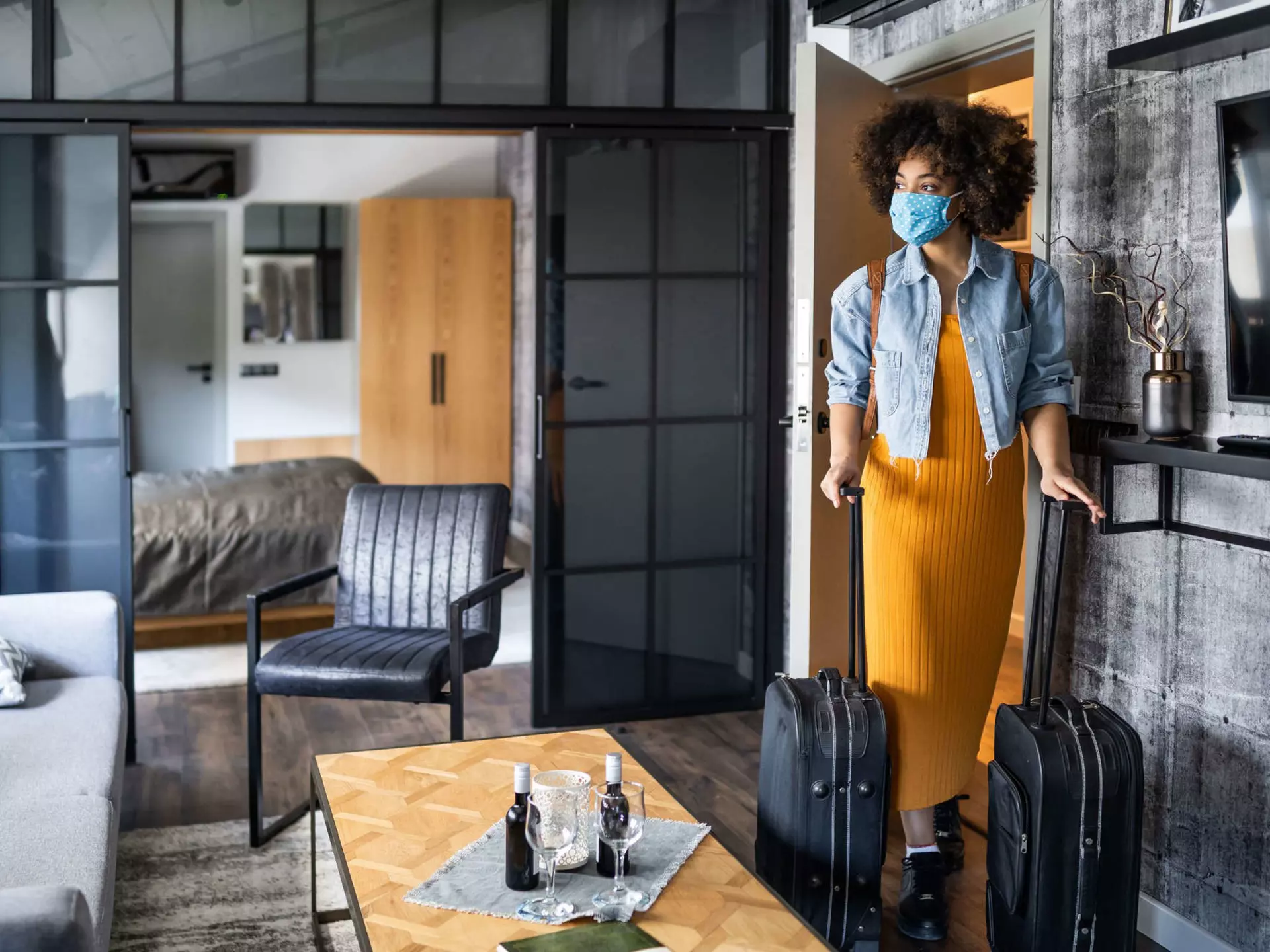 Woman with protective face mask arriving in hotel room.