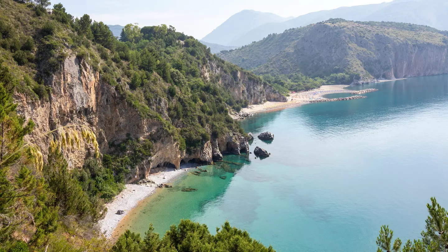 Mountainous landscape with white sandy beach and blue sea